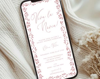 May include: A mobile phone screen shows a bridal shower invitation. The invitation has the text "Viva la Novia!" in a flowing script, surrounded by a pink floral border. The invitation also includes the bride's name, date, time, and location details.