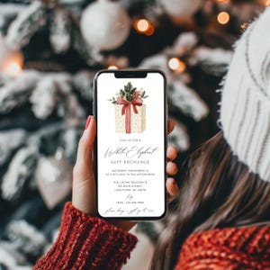 Peut inclure: Un &eacute;cran de smartphone affichant une invitation num&eacute;rique pour un &eacute;change de cadeaux White Elephant. Le design pr&eacute;sente une illustration &agrave; l'aquarelle d'un cadeau avec un n&oelig;ud rouge et des branches de pin, avec les d&eacute;tails de l'&eacute;v&eacute;nement.