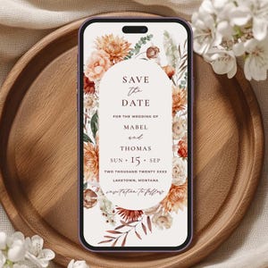 Może przedstawiać: Zaproszenie na ślub "Save the Date" z kwiatowym wzorem w kolorze pomarańczowym, brzoskwiniowym i białym. Tekst brzmi: "Save the Date na ślub Mabel i Thomasa, Niedz. 15. Wrz. Dwa Tysiące Dwudziesty XXXX, Laketown, Montana."