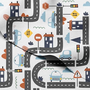 May include: White fabric with a repeating pattern of roads, cars, houses, and traffic signals. The roads are gray with white dashed lines. Cars are light blue. Houses have orange roofs. Traffic signals show red, yellow, and green lights.