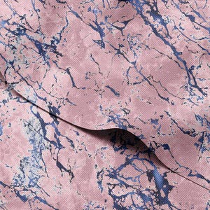 Pode incluir: Close-up de um tecido com um padrão de mármore rosa. O design apresenta veios azuis escuros sobre um fundo rosa. O tecido tem uma aparência texturizada, com um padrão tecido sutil.
