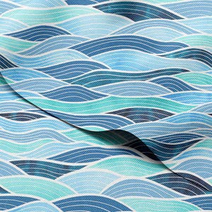 Può includere: Un tessuto con un motivo a onde ripetute in tonalità di blu e verde acqua. Il design presenta linee curve che creano un senso di movimento, con un angolo piegato che rivela la trama del tessuto. L'estetica generale ricorda l'oceano.