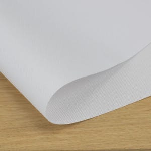 a close-up view of a white, textured surface, possibly a piece of paper or fabric, resting on a wooden surface.