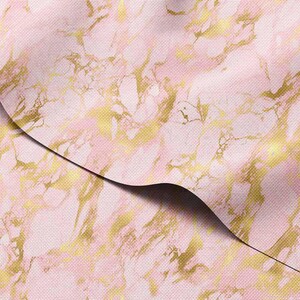 Pode incluir: Tecido com padrão de mármore rosa e dourado. O design apresenta padrões em espiral de rosa e dourado, criando uma aparência luxuosa e elegante. O tecido está dobrado, revelando a parte inferior.