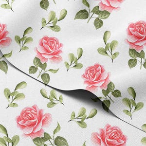 Op de afbeelding: Witte stof met een herhaald patroon van roze rozen en groene bladeren. De rozen staan in volle bloei en de bladeren zijn een mix van licht- en donkergroen. De stof heeft een licht getextureerd uiterlijk.