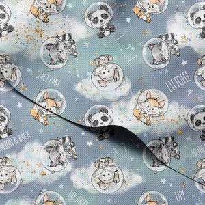Puede incluir: Una tela azul claro con un patrón repetido de animales de dibujos animados con cascos espaciales. Los animales incluyen pandas, zorros, mapaches y ovejas. Las palabras "SPACE BABY", "LIFTOFF!" y "TO THE MOON & BACK" son visibles.