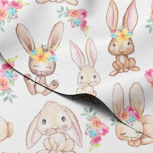 May include: White fabric featuring a repeating pattern of watercolor bunnies with floral crowns and bouquets. The bunnies are in various poses, with soft brown and beige fur, and pink-lined ears. The floral accents include pink, blue, and yellow flowers.