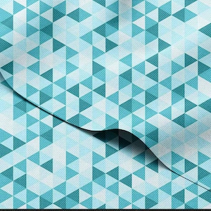 May include: A fabric with a geometric pattern of teal, light blue, and white triangles. The triangles are arranged in a repeating pattern, creating a textured appearance. The fabric is folded over, revealing the pattern on both sides.
