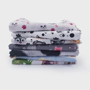 A stack of colorful fabric pieces with various animal and cartoon-like patterns, including cats, dogs, and other animals.