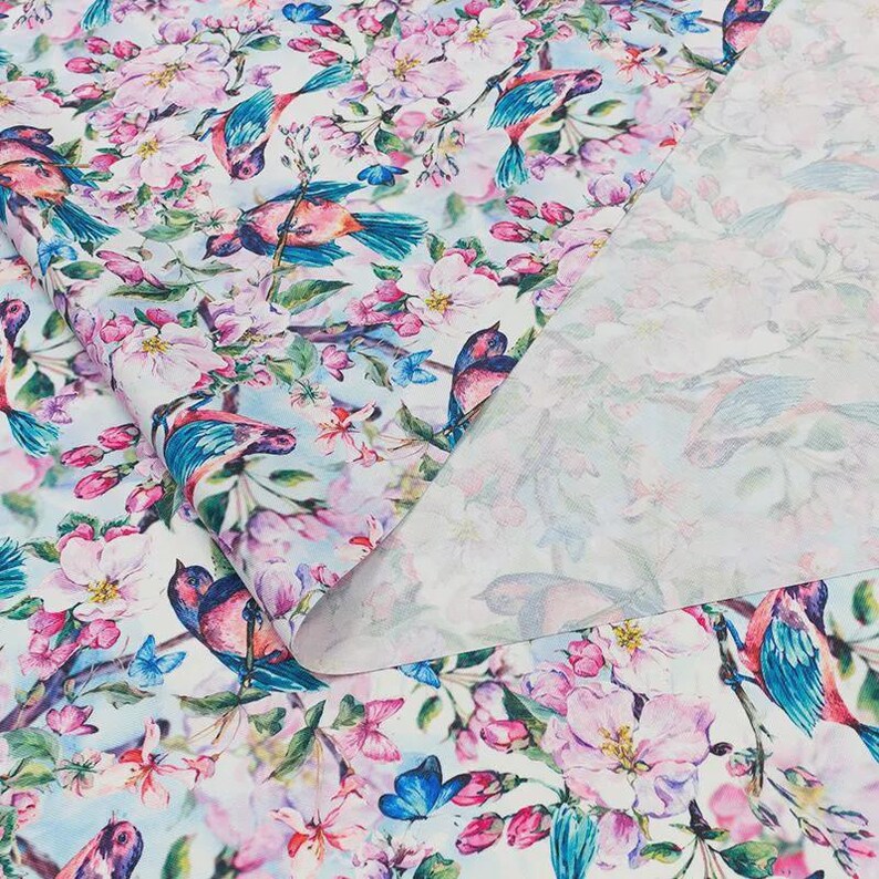 a vibrant and colorful floral print with various birds and flowers, including pink, blue, and green elements. The print appears to be a textile or fabric with a repeating pattern of these floral and bird motifs.