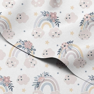 Puede incluir: Tela blanca con un patrón repetido de arcoíris pastel, nubes esponjosas y detalles florales. Los arcoíris presentan colores suaves como el amarillo, el azul y el rosa. Las nubes tienen detalles de corazón y las flores son rosas.