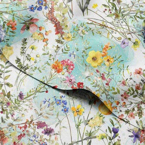 May include: Floral fabric with a watercolor effect. The design features a variety of colorful wildflowers in shades of yellow, pink, orange, and purple, set against a light blue and white background. The fabric has a delicate, airy feel.