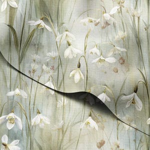 Puede incluir: Una tela con un estampado floral de campanillas blancas y tallos verdes sobre un fondo suave y apagado. El diseño tiene un efecto de acuarela, con una sombra oscura y curvada en la imagen.