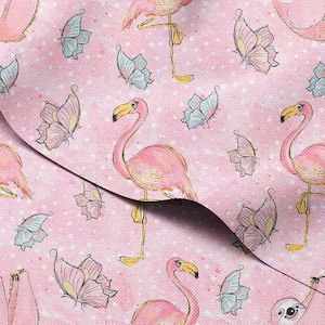 May include: Pink fabric with a repeating pattern of pink flamingos and butterflies in shades of pink, blue, and yellow. The background is a light pink with white polka dots. The fabric is folded, showing the pattern's continuity.