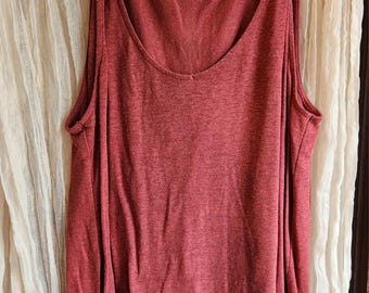May include: A red sleeveless tank top with a knotted detail on the straps. The tank top is hanging on a wooden hanger with a price tag that says "5".