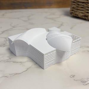 以下が含まれることがあります： 湾曲した屋根部分、ドーム型の構造、外壁に詳細な格子状の窓パターンを備えた、白い3Dプリント建築模型。単色のミニチュアとして表現された建物群の構造体です。