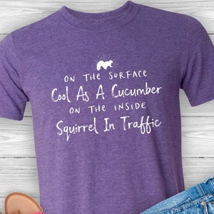 May include: Purple t-shirt with white text that reads "On the surface cool as a cucumber on the inside squirrel in traffic".