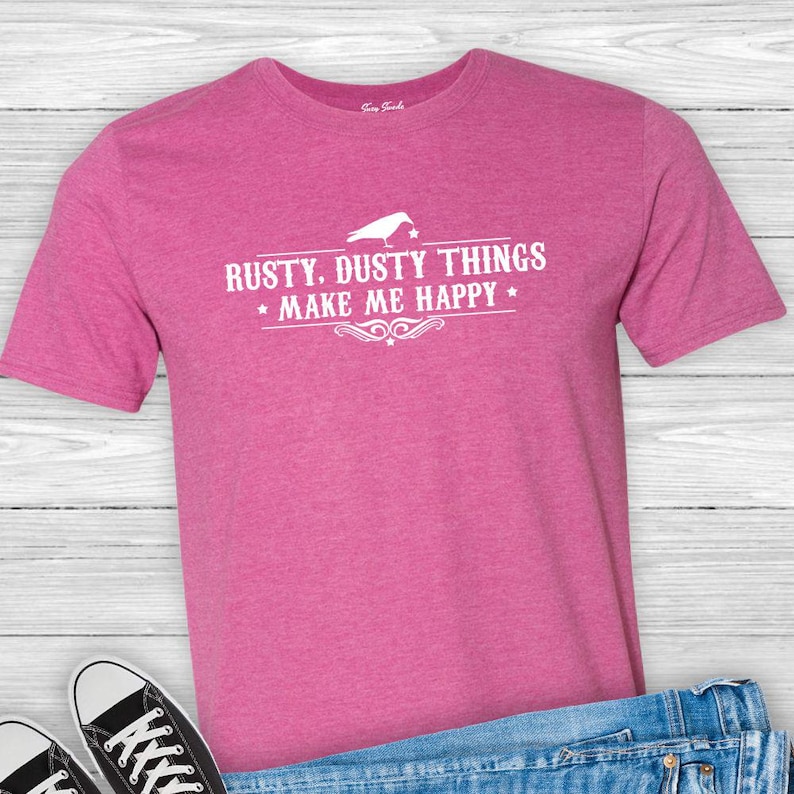 Puede incluir: Camiseta rosa con un gr&aacute;fico blanco que dice "Rusty. Dusty Things Make Me Happy" con un dise&ntilde;o de p&aacute;jaro.