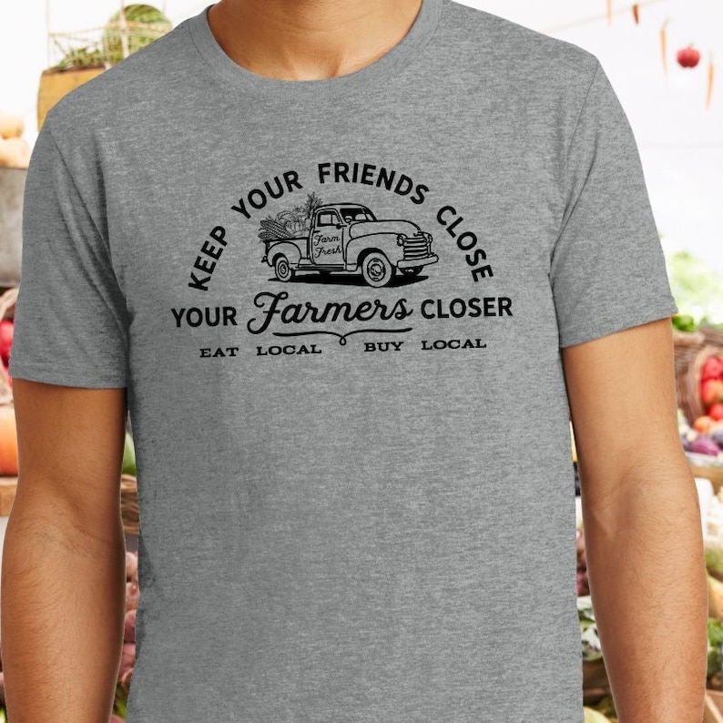 May include: Gray t-shirt with a black graphic of a pickup truck with a sign that says "Farm Fresh" and the text "Keep your friends close, your farmers closer. Eat local, buy local."