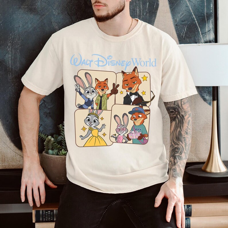 Puede incluir: Camiseta color crema con un dise&ntilde;o de personajes de la pel&iacute;cula Zootr&oacute;polis, incluyendo a Judy Hopps y Nick Wilde. El texto "Walt Disney World" est&aacute; impreso en azul claro encima del dise&ntilde;o.