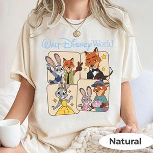Puede incluir: Camiseta color crema con un gr&aacute;fico de dibujos animados de personajes de Zootopia. El dise&ntilde;o incluye a Judy Hopps, Nick Wilde y otros personajes en un dise&ntilde;o de cuatro paneles. El texto "Walt Disney World" est&aacute; arriba.