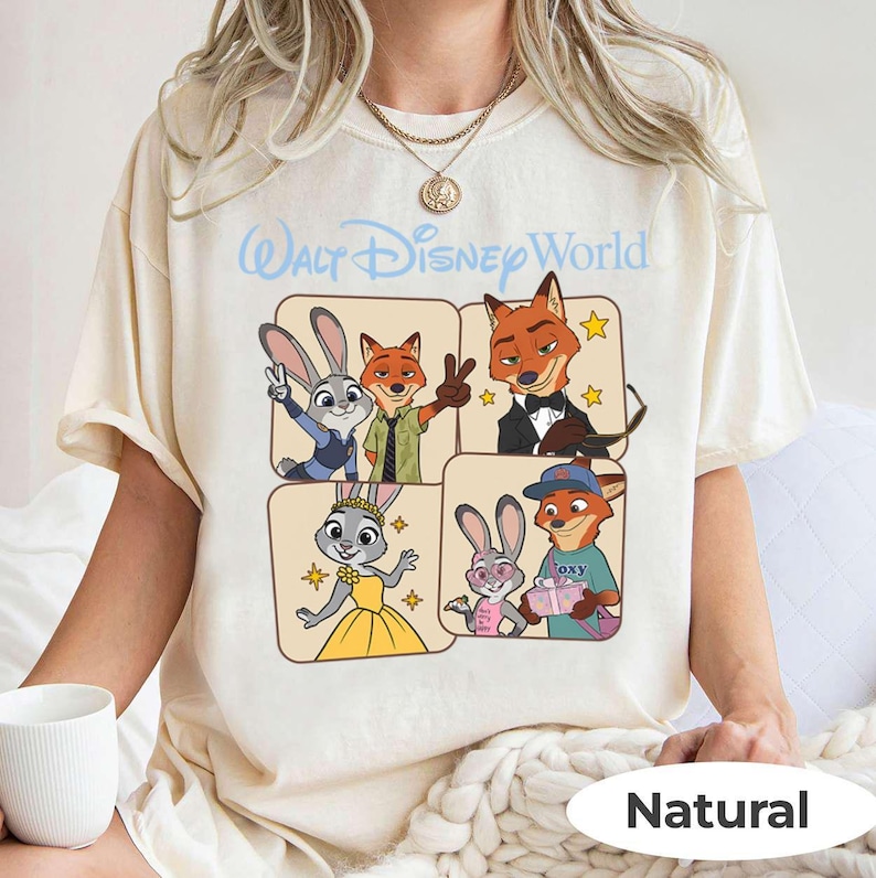 Puede incluir: Camiseta color crema con un gr&aacute;fico de dibujos animados de personajes de Zootopia. El dise&ntilde;o incluye a Judy Hopps, Nick Wilde y otros personajes en un dise&ntilde;o de cuatro paneles. El texto "Walt Disney World" est&aacute; arriba.