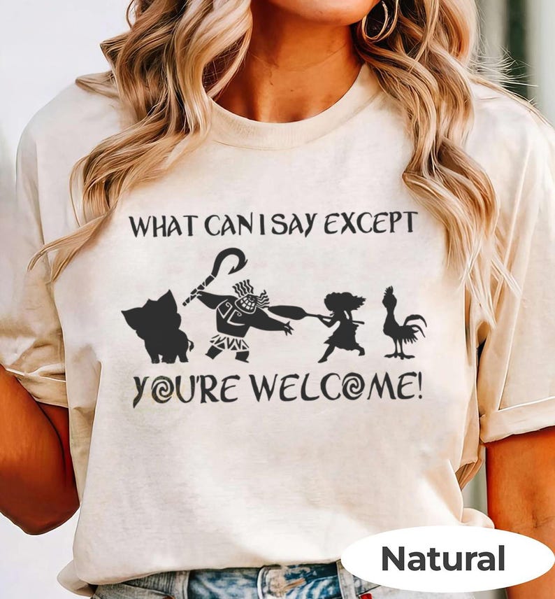 Puede incluir: Camiseta beige con la frase "WHAT CAN I SAY EXCEPT YOU'RE WELCOME!" y siluetas de personajes de la pel&iacute;cula Moana. La camiseta tiene cuello redondo y mangas cortas. La palabra "Natural" est&aacute; impresa en la parte inferior.