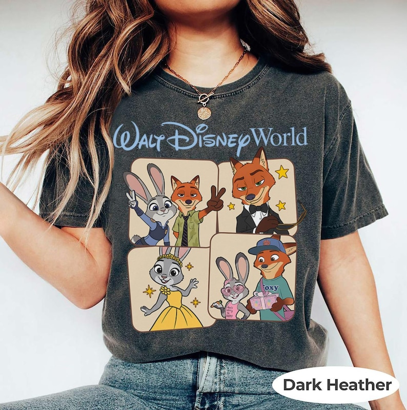 Puede incluir: Camiseta gris jaspeado oscuro con las palabras "Walt Disney World" en escritura azul sobre un gr&aacute;fico de cuatro paneles de personajes de Zootopia. El gr&aacute;fico incluye a Judy Hopps y Nick Wilde. La camiseta es de material suave.
