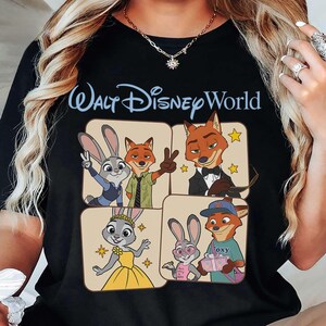 Puede incluir: Camiseta negra con la inscripci&oacute;n "Walt Disney World" en azul claro. La camiseta muestra personajes de dibujos animados de la pel&iacute;cula Zootr&oacute;polis en cuatro paneles cuadrados. Los personajes incluyen un conejo y un zorro.
