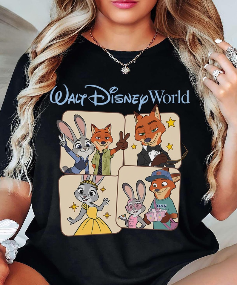 Puede incluir: Camiseta negra con la inscripci&oacute;n "Walt Disney World" en azul claro. La camiseta muestra personajes de dibujos animados de la pel&iacute;cula Zootr&oacute;polis en cuatro paneles cuadrados. Los personajes incluyen un conejo y un zorro.
