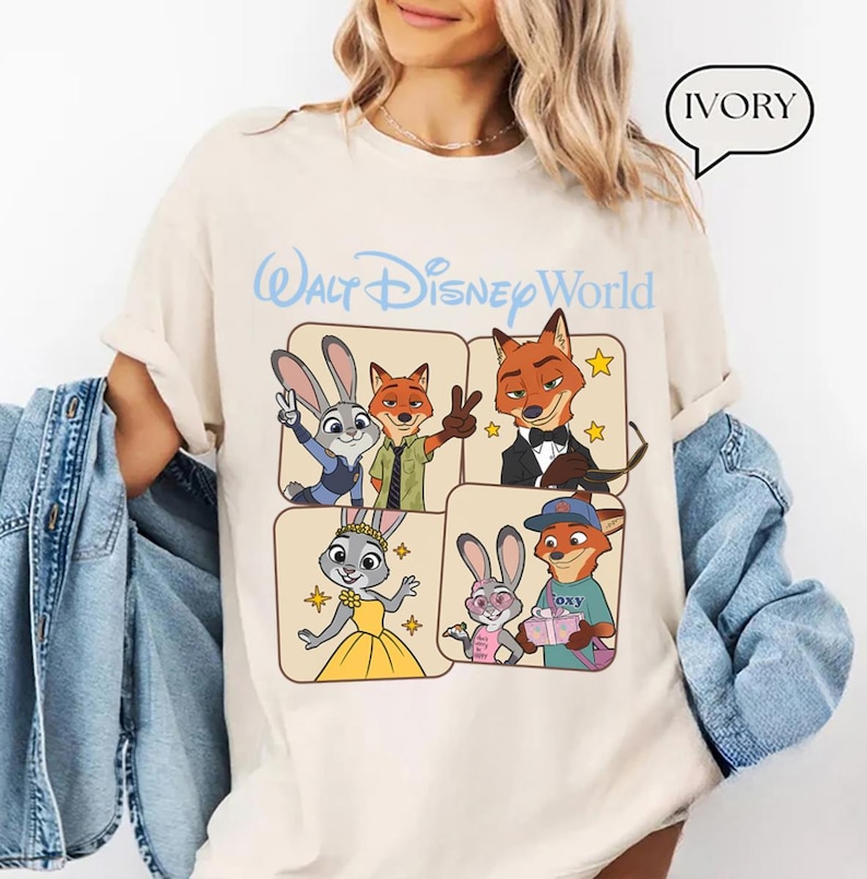Puede incluir: Camiseta de color marfil con un gr&aacute;fico de personajes de la pel&iacute;cula Zootopia y el texto "Walt Disney World" en azul claro. El dise&ntilde;o incluye a Judy Hopps y Nick Wilde.