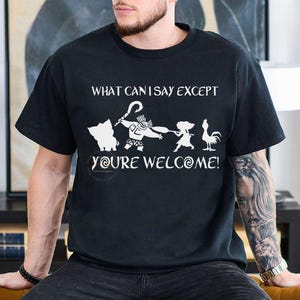 Puede incluir: Camiseta negra con un dise&ntilde;o gr&aacute;fico blanco con personajes y texto de la pel&iacute;cula "Vaiana". El texto dice "WHAT CAN I SAY EXCEPT YOU'RE WELCOME!" en una fuente divertida. El dise&ntilde;o incluye un cerdo, Maui y un gallo.