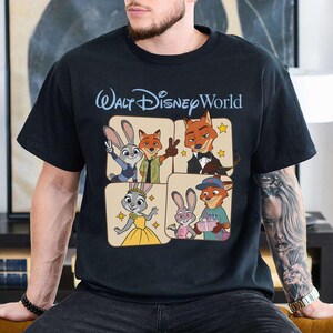 Puede incluir: Camiseta negra con un dise&ntilde;o gr&aacute;fico de personajes de la pel&iacute;cula Zootr&oacute;polis, incluyendo a Judy Hopps y Nick Wilde, con el texto "Walt Disney World" en azul claro. El dise&ntilde;o est&aacute; en formato de cuadr&iacute;cula con cada personaje en un cuadrado separado.
