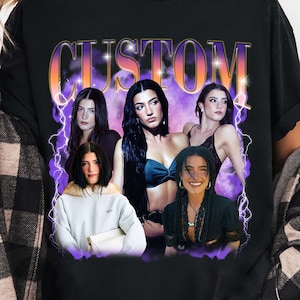 May include: Black t-shirt featuring a graphic design with the word "CUSTOM" in an orange and purple gradient font. The design includes images of several women. The shirt is worn by a person wearing a black and white plaid shirt.