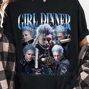 May include: Black t-shirt with a graphic print of a group of characters from the video game Devil May Cry. The text "GIRL DINNER" is printed in blue letters above the characters.