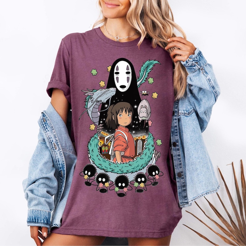 Może przedstawiać: Fioletowy T-shirt z nadrukiem graficznym postaci z filmu animowanego Spirited Away. Grafika przedstawia Chihiro, Bez Twarzy i ducha rzeki.