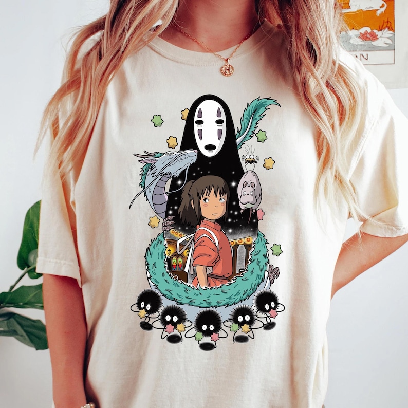 Może przedstawiać: Biała koszulka z nadrukiem graficznym postaci z filmu animowanego Spirited Away. Grafika przedstawia Chihiro, Bez Twarzy i ducha rzeki.