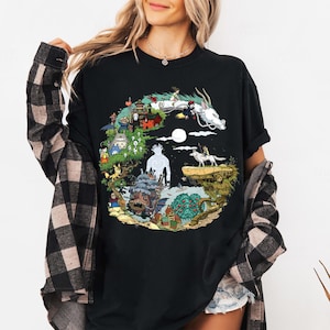 K&ouml;nnte beinhalten: Schwarzes T-Shirt mit einem farbenfrohen Grafikdesign, das Charaktere und Szenen aus einem beliebten Zeichentrickfilm zeigt. Das Design umfasst einen wei&szlig;en Drachen, ein M&auml;dchen und andere animierte Figuren. Das T-Shirt ist ein bequemer, l&auml;ssiger Stil.