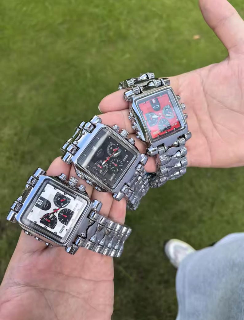 May include: Three square-faced wristwatches with silver metal link bands. The watch faces are black, white, and red, with multiple dials and the brand name "BAILEE". The watches are held against a green background.