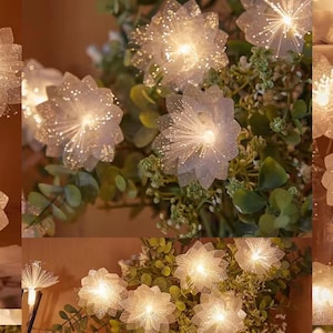 May include: Close-up of a floral arrangement featuring illuminated, white, fiber optic flowers. The flowers are clustered among green foliage, creating a soft, glowing effect. The lights are warm and inviting.