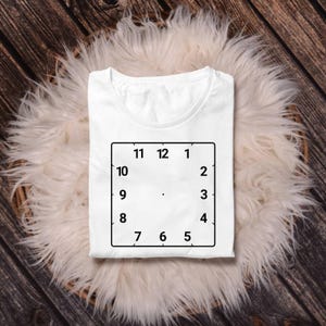May include: White t-shirt with a black outline of a clock face with numbers 1 through 12.