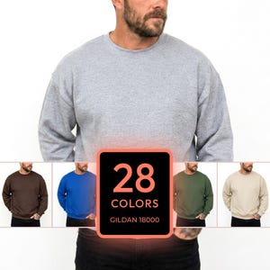 May include: A grey crewneck sweatshirt worn by a person, with a central graphic box displaying the text 28 COLORS GILDAN 18000. Below, four smaller images show the same sweatshirt style in brown, blue, olive green, and beige colors.