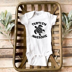 May include: White baby onesie with a black graphic of a turtle and the text "TURTLEY AWESOME".