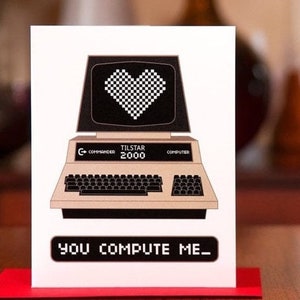 May include: A white card with a black and white illustration of a retro computer with a heart on the screen. The computer is labeled "Tilstar 2000". The text "You Compute Me" is printed below the computer.