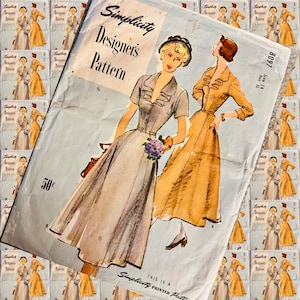 Puede incluir: Un patrón de costura vintage Simplicity Designer's Pattern para un vestido. El patrón es para la talla 14, busto 32. El patrón presenta a dos mujeres con vestidos, una con un vestido gris claro y la otra con un vestido beige. El patrón está impreso sobre un fondo azul claro con el texto "Simplicity Designer's Pattern" en negro.