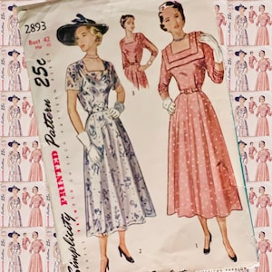 May include: Vintage Simplicity sewing pattern number 2893 for a dress. The pattern is for a size 42 bust and includes three different styles. The first style is a pink dress with a white polka dot pattern. The second style is a white dress with a floral pattern. The third style is a pink dress with a square neckline.