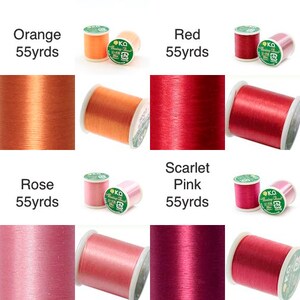 K&ouml;nnte beinhalten: Eine Auswahl an Garnrollen in verschiedenen Farben, darunter Orange, Rot, Rose und Scharlachrosa. Jede Spule ist mit der Farbbezeichnung und dem Text "55 yds" versehen. Das Garn ist auf wei&szlig;en Spulen aufgewickelt.
