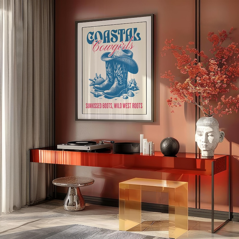 May include: A framed poster with the text "Coastal Cowgirls" in blue and pink lettering. The poster features a pair of blue cowboy boots with a cowboy hat on top. The text "Sunkissed Boots, Wild West Roots" is below the boots.