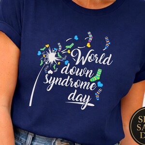 May include: Navy blue t-shirt featuring a dandelion design and the text "World down syndrome day". The dandelion seeds are replaced with colourful socks and hearts. A round sticker with the words "SHIP SAME DAY" is on the bottom right.