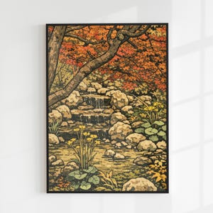 以下が含まれることがあります： 穏やかな日本の庭園の風景を描いた、額入りのアートプリント。このアートワークは、岩の上を流れ落ちる小さな滝と、オレンジと赤の色合いの鮮やかな紅葉が特徴です。黄色いワイルドフラワーと緑のスイレンの葉が、穏やかな風景に彩りを添えています。
